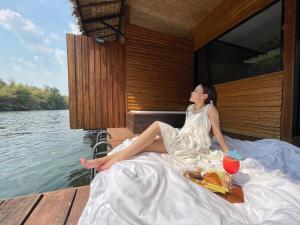 una mujer con un vestido blanco sentada en un barco en The Hub Erawan Resort, en Chongsadao