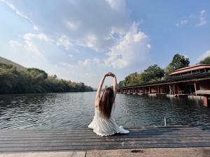 崇貞夫的住宿－The Hub Erawan Resort，坐在水体附近的码头上的女孩