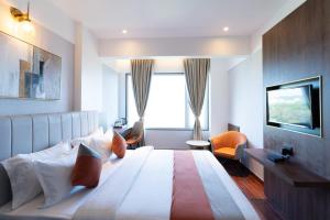 ein Hotelzimmer mit einem großen Bett und einem Fenster in der Unterkunft The Royal Pavilion, Kolhapur in Kolhapur