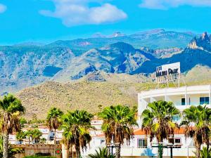 ein Gebäude mit Palmen und Bergen im Hintergrund in der Unterkunft LaVITALSOL in Adeje