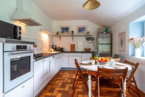 a kitchen with a table and chairs and a kitchen with white cabinets at Kerfeunteun - Grande maison à 15min de la plage in Quimperlé +7 photos