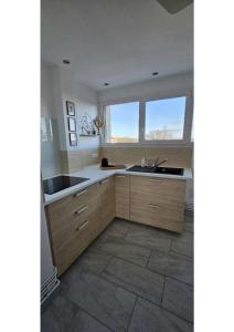 uma cozinha com armários de madeira, um lavatório e uma janela em Superbe T3 cosy, parking gratuit + balcon em Riom