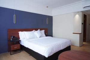 a bedroom with a large bed and a blue wall at Stay 'd Kuningan in Jakarta