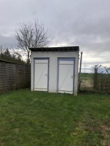 a white shed with two doors in a yard at Les Chalets de Babeth et Cathy 