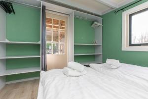 een groene kamer met 2 bedden en een raam bij Chalet - Dorpsstraat 25 - Biggekerke 'De Weide Blick' in Biggekerke