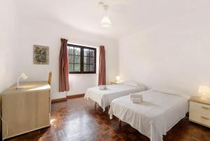 a hotel room with two beds and a window at Alto da Praia Villa in Colares