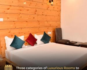1 cama blanca con 4 almohadas en una habitación en Hotel The Crown, Dharamshala, en Dharamshala