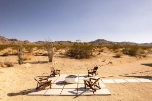 three chairs sitting on a blanket in the desert at Joshua Tree Luxury Home With Hot Tub & views in Joshua Tree