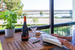 a person reading a book on a table with a bottle of wine at Pedras D'el Rei in Tavira