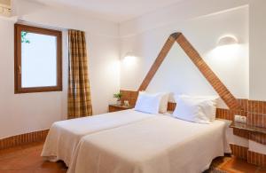 a bedroom with a large white bed with a window at Pedras D'el Rei in Tavira