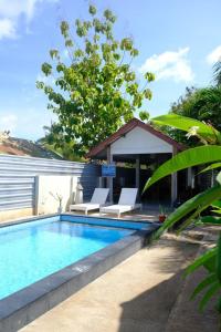 a swimming pool with two chairs and a house at Rumah DOLE in Gili Islands