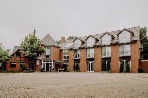 un grand bâtiment en briques rouges avec de nombreuses fenêtres dans l'établissement Auehof Hotel & Restaurant, à Garrel