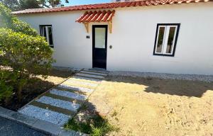 een wit huis met een zwarte deur en een oprit bij Pine & Apple Beach House in Colares