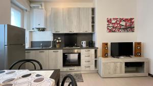 uma cozinha com armários brancos, uma televisão e uma mesa em La casa di Ange - Affitti Brevi Italia em Lecco