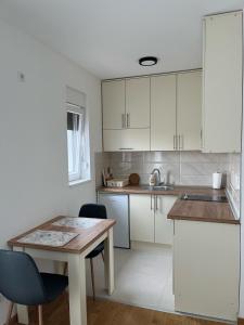 a kitchen with white cabinets and a wooden table at Apartment 24 in Bijeljina