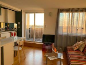 ein Wohnzimmer mit einem Sofa und einem Tisch sowie eine Küche in der Unterkunft Rooftop terrasse 360° hypercentre in Toulouse