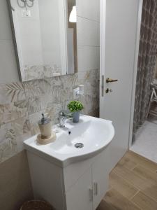 een badkamer met een witte wastafel en een spiegel bij L'Angolo di Sarah in Santo Stefano di Camastra