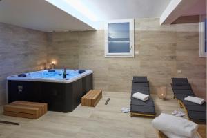 La grande salle de bains est pourvue d'un bain à remous et de chaises. dans l'établissement Luci di Assisi B&B Wellness, à Assise