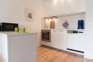 uma cozinha com electrodomésticos brancos e armários brancos em Ferienwohnung Saphir em Schilksee