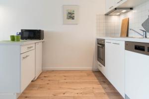 eine Küche mit weißen Schränken und Holzböden in der Unterkunft Ferienwohnung Saphir in Schilksee