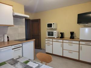 une cuisine avec des armoires blanches et des appareils électroménagers blancs dans l'établissement L'Orée du Bois, à Dossenheim-sur-Zinsel