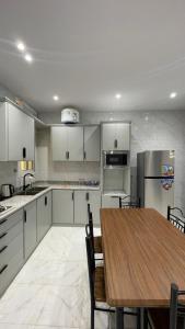 uma cozinha com uma mesa de madeira e uma cozinha com armários brancos em شقة غرفتين وصاله em Al ‘Uqūl