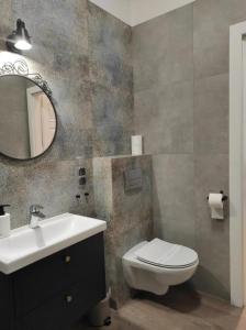 a bathroom with a sink and a toilet and a mirror at Lawendowy - Apartamenty Smart Projekt in Tarnów