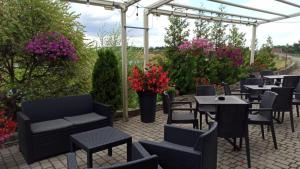 een patio met tafels, stoelen en bloemen bij Hotel Forma in Piła