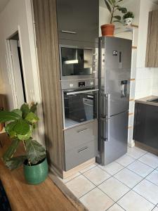eine Küche mit einem Kühlschrank aus Edelstahl und einem Backofen in der Unterkunft Le cocon du stade de France in Saint-Denis