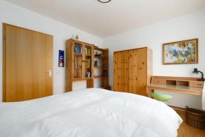 1 dormitorio con 1 cama blanca grande y armarios de madera en Villa Foerdestrand _ Spinnaker, en Laboe