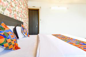 ウダイプールにあるFabHotel King Mansionのカラフルな枕付きのベッドが備わるホテルルームです。