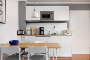 a kitchen with a wooden table and white cabinets at Kapitaenshaus 10 in Laboe