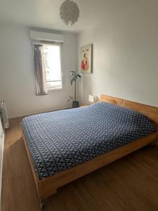 een slaapkamer met een bed met een blauw dekbed bij Le cocon du stade de France in Saint-Denis
