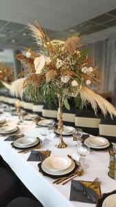 a long table with plates and a vase of flowers at Hotel Forma in Piła