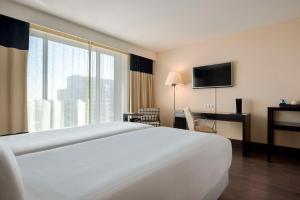 a hotel room with a bed and a large window at NH Den Haag in The Hague