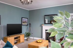 sala de estar con TV y chimenea en The Stirling Townhouse en Stirling