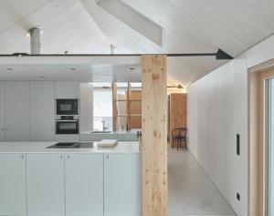 een keuken met witte kasten en een houten paal bij TIROLER TRIS Chalet & Penthouse in Maurach