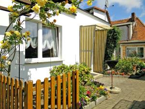 ein weißes Haus mit einem Holzzaun und Blumen in der Unterkunft Apartments Greifswalder Chaussee in Stralsund