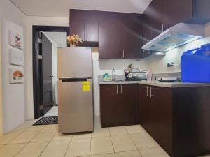 a kitchen with brown cabinets and a stainless steel refrigerator at 1 bedroom in Pioneer Woodlands Condo near Mrt Boni Mandaluyong in Manila