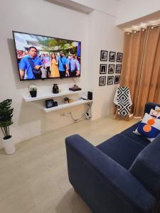 a living room with a blue couch and a flat screen tv at 1 bedroom in Pioneer Woodlands Condo near Mrt Boni Mandaluyong in Manila