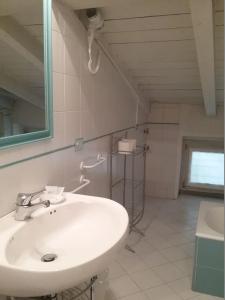 La salle de bains blanche est pourvue d'un lavabo et d'un miroir. dans l'établissement Artemisia Antique Rooms Fara, à Vaprio dʼAdda