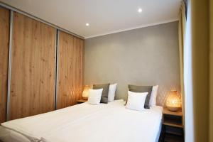 1 dormitorio con 1 cama blanca grande y 2 lámparas en Folga Resort en Mrzeżyno