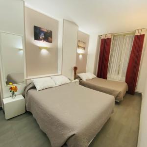 two beds in a hotel room with red curtains at Hôtel Paris Gambetta in Paris