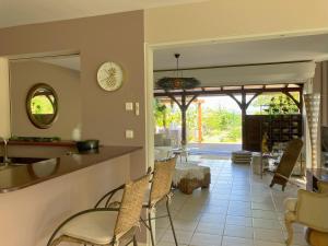 a kitchen with a counter and chairs and a mirror at Terracota - Spacieux et Chaleureux avec extérieur in Les Trois-Îlets