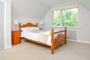 sypialnia z drewnianym łóżkiem i oknem w obiekcie Ellie's Farmhouse w mieście Ard Fhearta