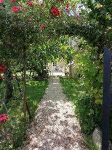 um jardim com um caminho com flores vermelhas e um arco em Chez Yvette & Shoji em Mauvezin