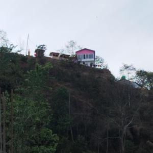 uma casa no topo de uma colina com árvores em Balthali himalaya view point restro em Panaoti