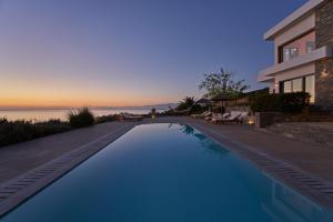 a swimming pool in front of a house at Elounda White Pearl Villa in Agios Nikolaos