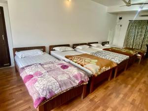 two beds in a room with wooden floors at Hotel Sova's Inn in Birātnagar