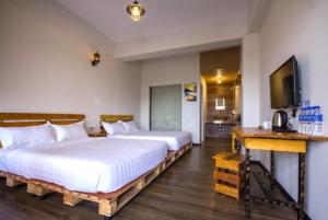 a bedroom with two beds and a flat screen tv at Kea Garden Guest House in Brinchang